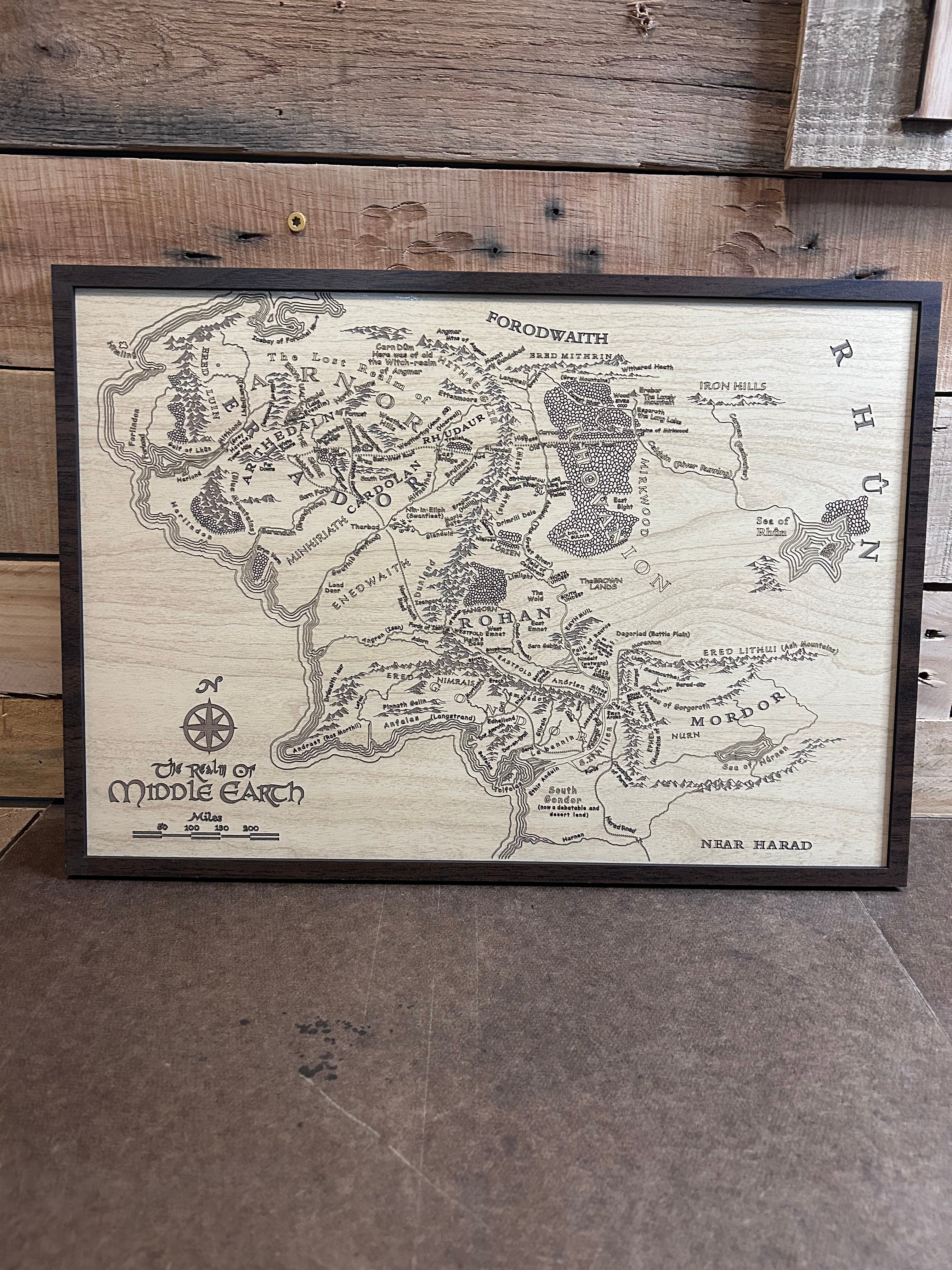 Wooden map of Middle-earth with 'The Lord of the Rings' branding on a wooden surface.