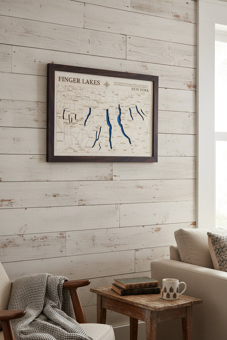 A framed Finger Lakes New York map wall art piece with blue lake outlines and a dark wood frame, mounted on a light gray wall.