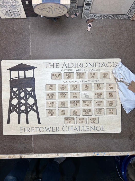 Wooden plaque with 'The Adirondack Firetower Challenge' design on workbench
