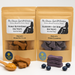 A package of Gluten-Free Peanut Butter Bones and a package of Blueberry + Oat Bones. Handmade organic dog treats from 'The Chosen Spot K9 Kitchen' with samples of treats displayed in front along with blueberries and a spoon of peanut butter.