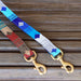 Two hand-woven cotton dog leashes in National Parks Collection patterns from a tail we could wag brand laying on a wooden bench
