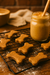 Peanut Butter Bones. Handmade organic dog treats from The Chosen Spot K9 Kitchen on a cooling rack with a jar of peanut butter in the background.