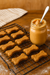 Bag of Peanut Butter Bone  handmade organic dog treats from The Chosen Spot K9 Kitchen on a cooling rack near a ar of penut butter.