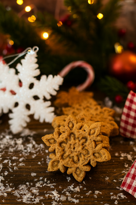 Peanut Butter Snowflakes from The Chosen Spot K9 Kitchen on a wooden surface with Christmas decorations in the background.