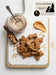 Peanut Butter Bones - handmade organic dog treats from The Chosen Spot K9 Kitchen on a white board with a jar of organic whole wheat flour and scattered peanuts.