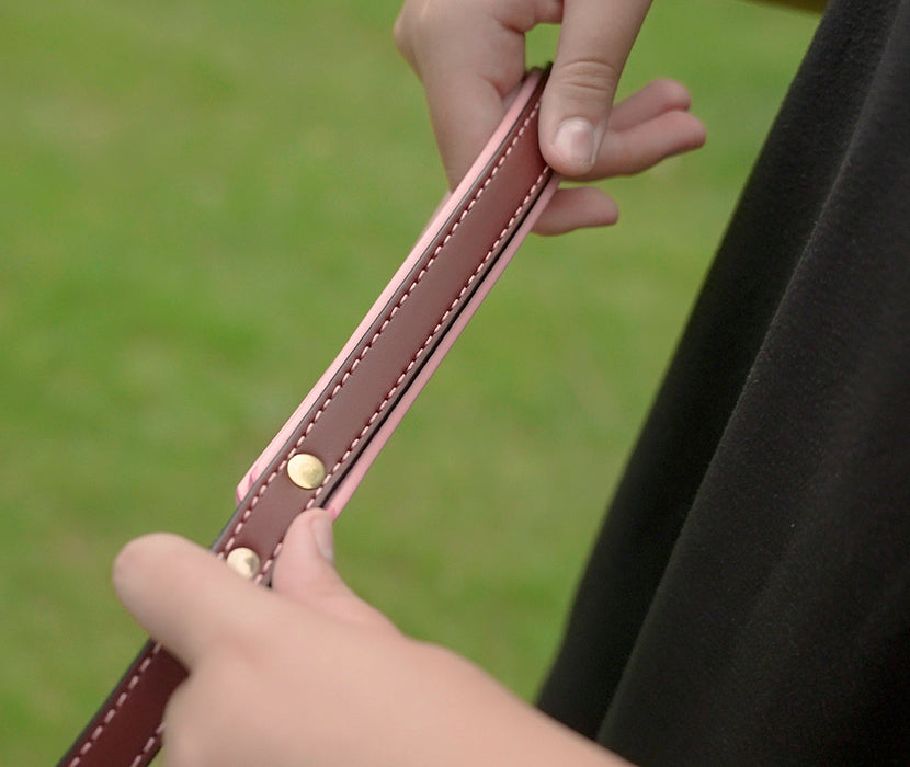 hands holding handle of Burgundy Padded Leash with Pink lining