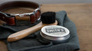 Smith's Leather Balm container with brush and cloth and a dog collar in the background