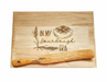 Wooden cutting board with engraved text and a spurtle.