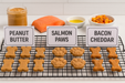  Peanut Butter Bones, Salmon Paws and Bacon Cheddar Biscuits with Duvall Farms Bacon Handmade organic dog treats from The Chosen Spot K9 Kitchen on a cooling rack with a white background.