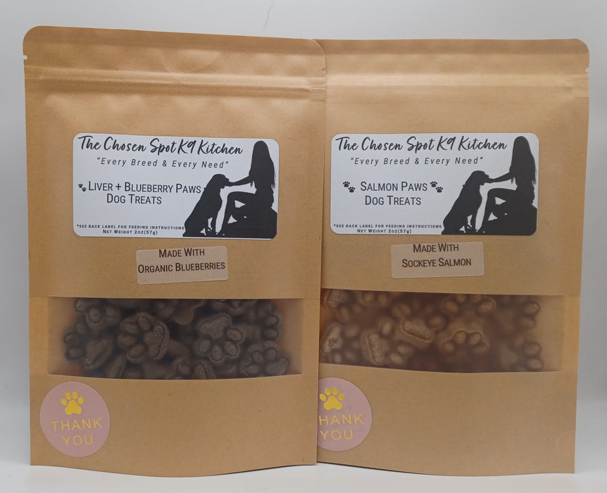 Two packages of handmade organic dog treats, one labeled 'Liver + Blueberry Paws' and the other 'Salmon Paws', from The Chosen Spot K9 Kitchen.