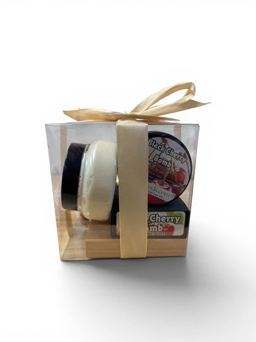Two small cylindrical products in a clear gift box with a gold ribbon on a white background.