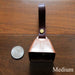 cowbell with antique brass finish and burgundy bridle leather strap shown next to a quarter