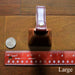 cowbell with antique brass finish and burgundy bridle leather strap shown next to a quarter and a ruler