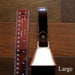 cowbell with antique brass finish and burgundy bridle leather strap shown next to a quarter and a ruler