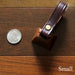 cowbell with antique brass finish and burgundy bridle leather strap shown next to a quarter