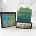 Green bath and body soap with a label on a white surface
