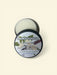 French Vanilla lotion bar in a tin with a label on a beige background