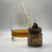 Jar of Hazy Fudge next to a glass with a wooden spoon