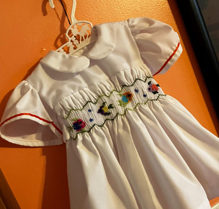 Smocked fish on a summer day. Baby girl dress-White with multicolored smocking, lined.