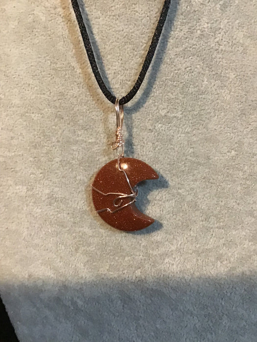 Wire wrapped Gold Red Sandstone crescent moon on a black satin cord.