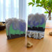 Two handmade soap bars with colorful swirls on a wooden surface.